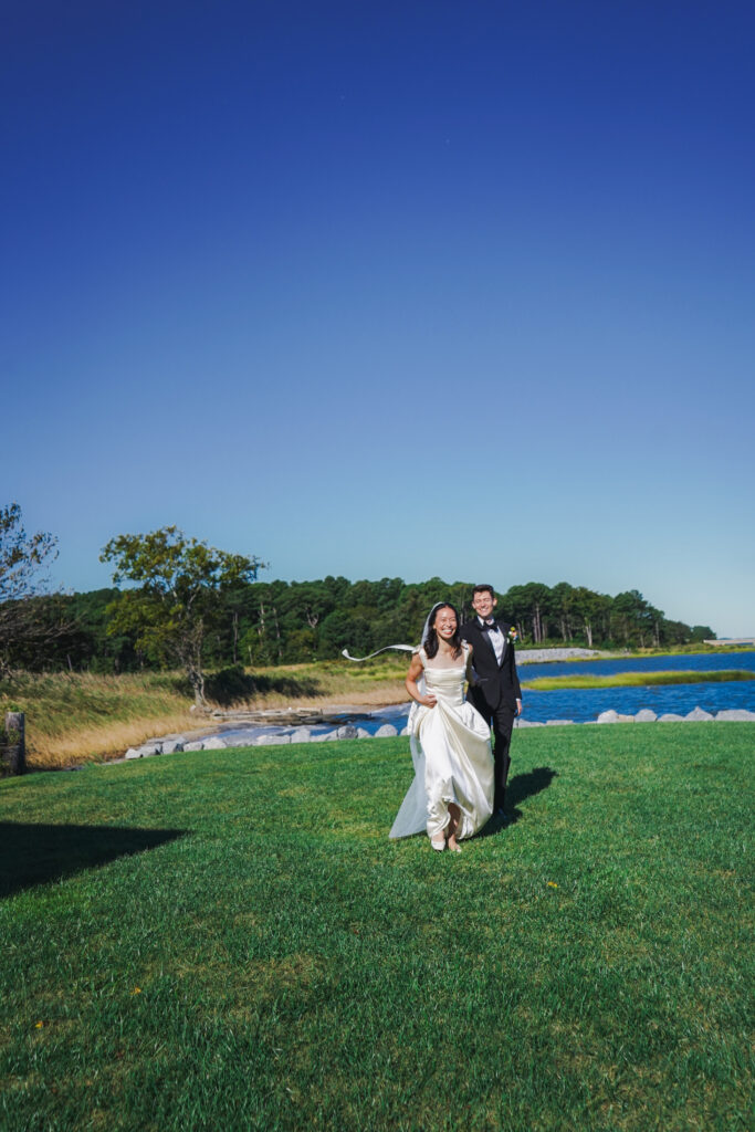 bride and groom walking with bay in background