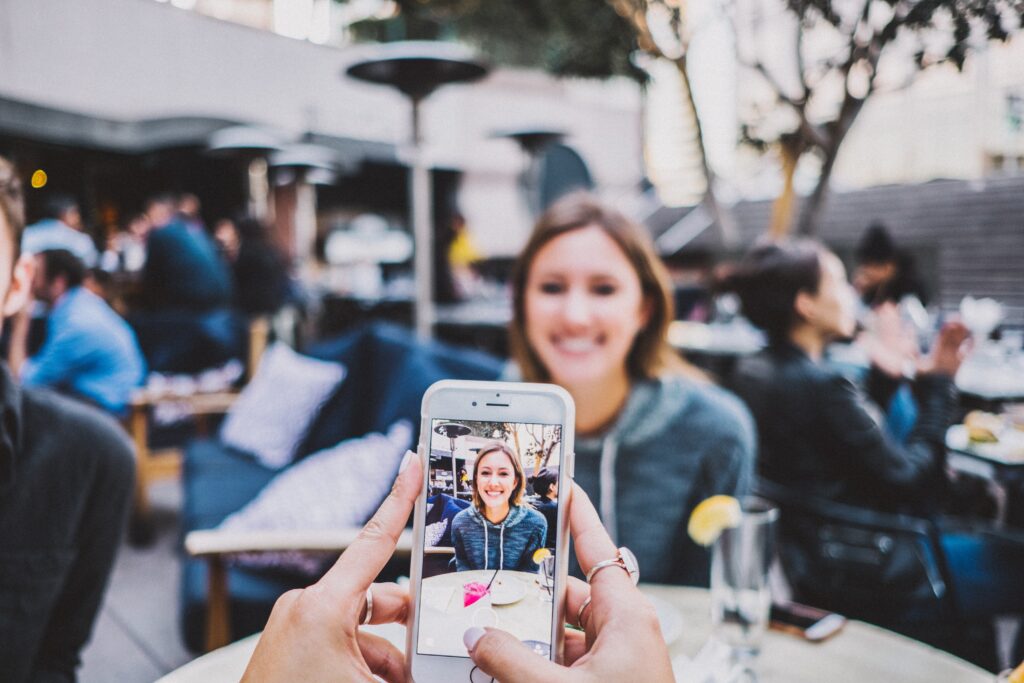 someone taking a photo of a woman at an outdoor restaurant