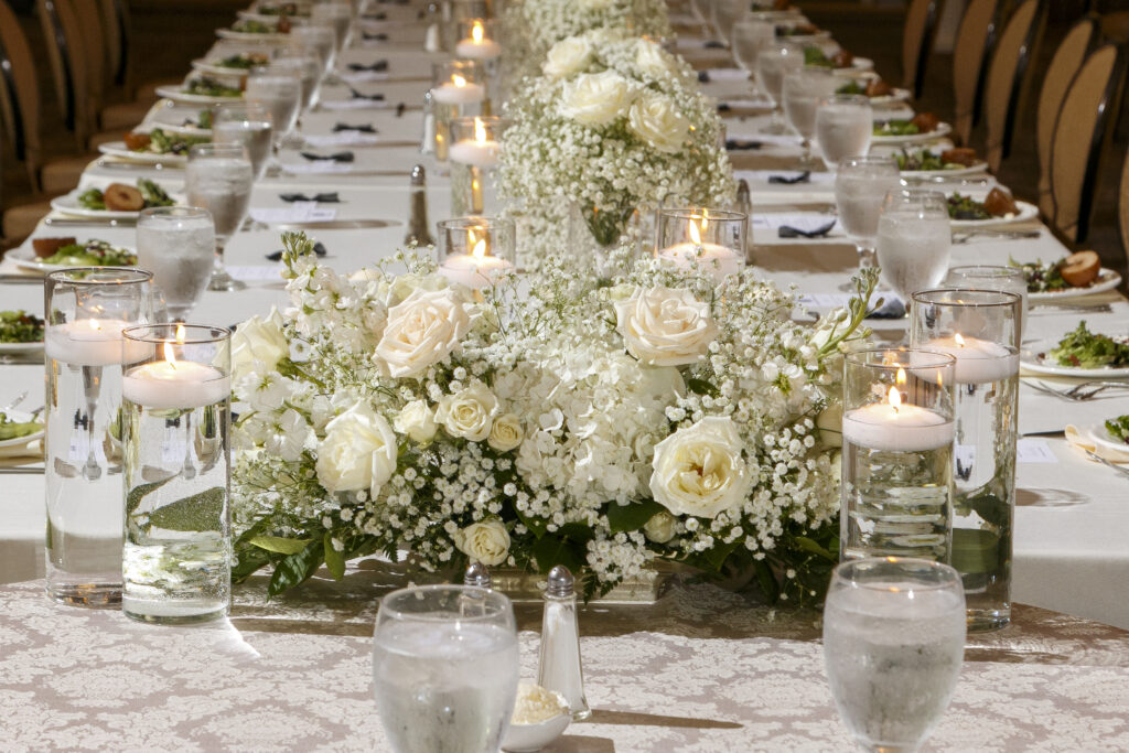 wedding reception table with floating candles and white roses