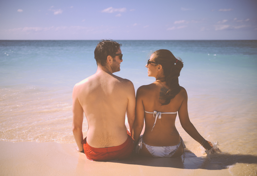 engaged couple on the beach looking at each other