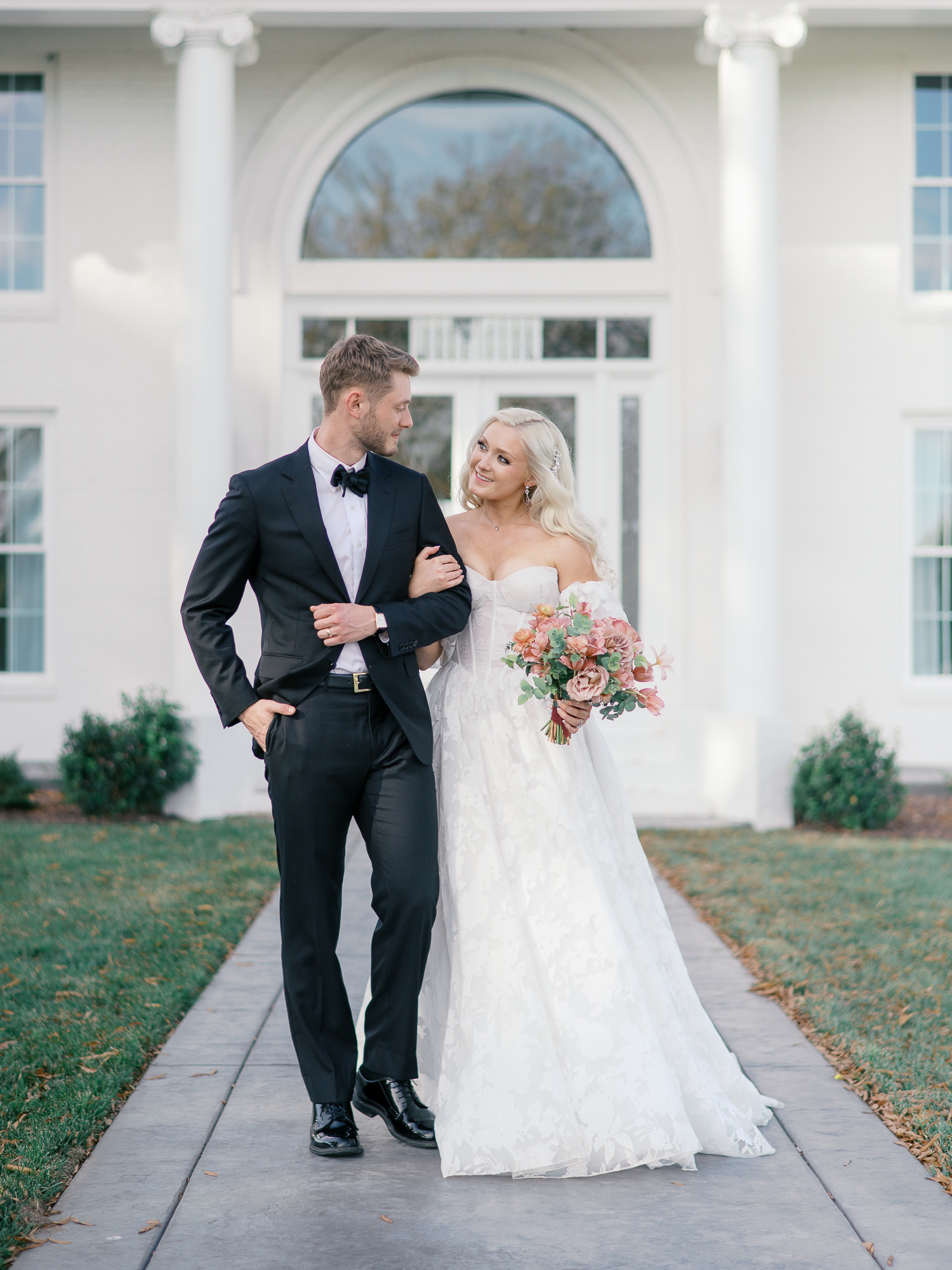 Bride and groom standing in front of the white-columned manor at Northfield Estate during their elegant Charlottesville wedding.