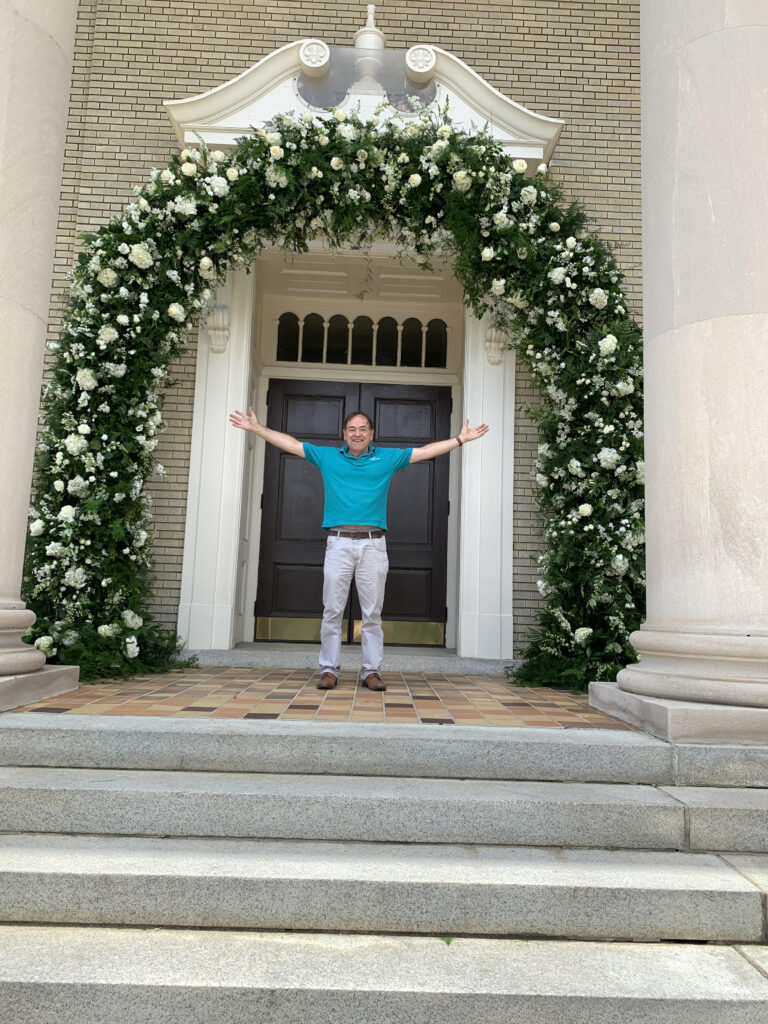 man standing under floral arch
